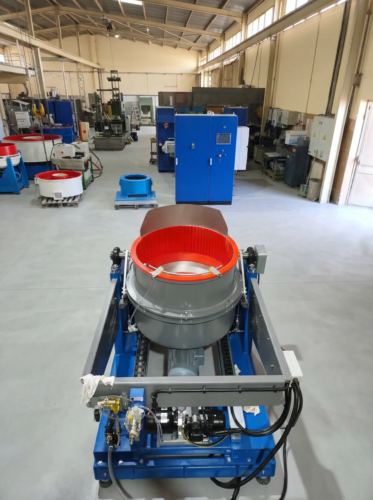 Vibrateurs circulaires, cuves et armoires de commande alignés le long de l'allée centrale.